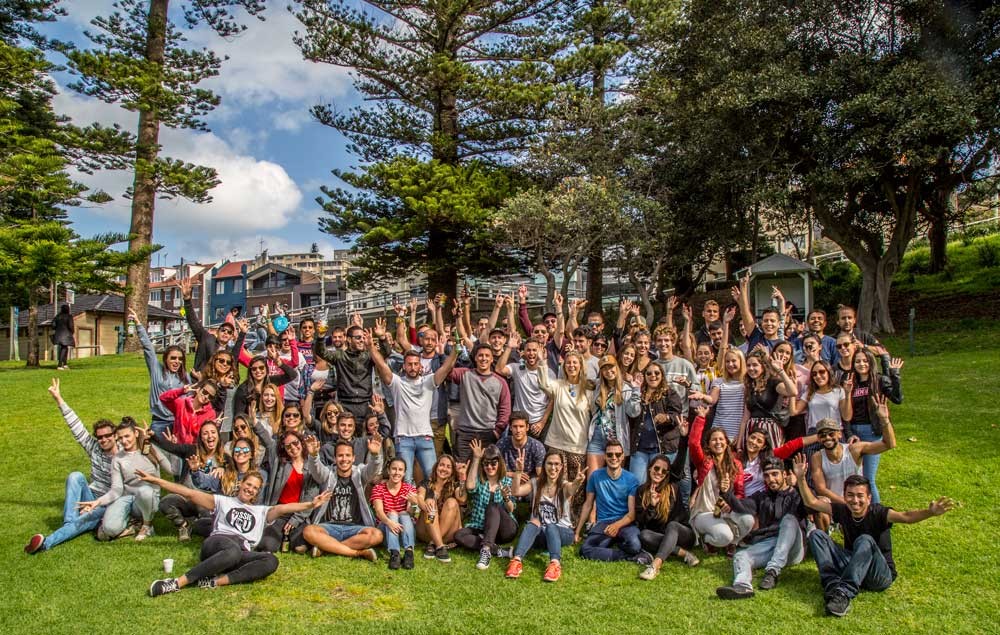 fotografía de un grupo de estudiantes posando a cámara en el césped y detrás la vegetación